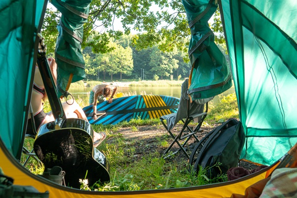Boy prepares to go supping while girlfriend sits in front of tent at a campsite