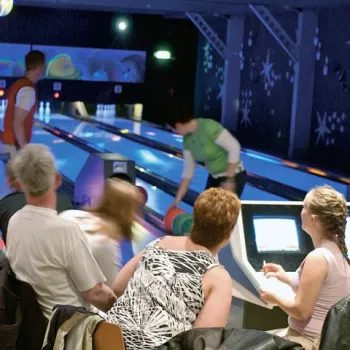 Groep mensen bowlt samen in een moderne bowlingbaan met sfeervolle verlichting en een gezellige sfeer.